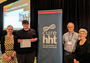 Dan Snelling receiving an award by a banner with Cure HHt on it. 