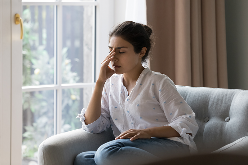 Stock image of a woman on a couch with her hand to her face