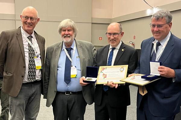 Heitman accepting award standing next to three colleagues